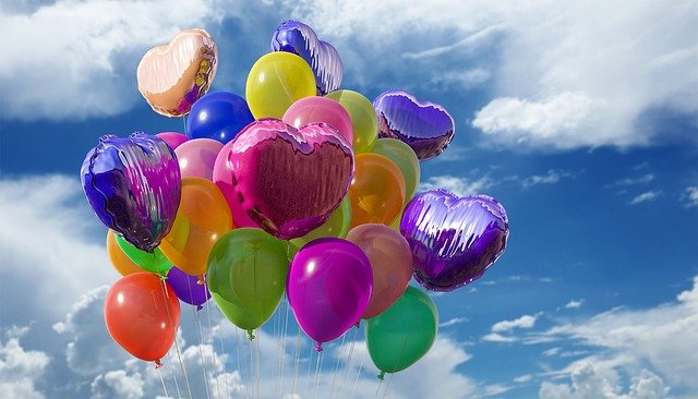 mehrere bunte Ballons an Fäden vor einem blauen Himmel bunte Ballons vor blauem Himmel